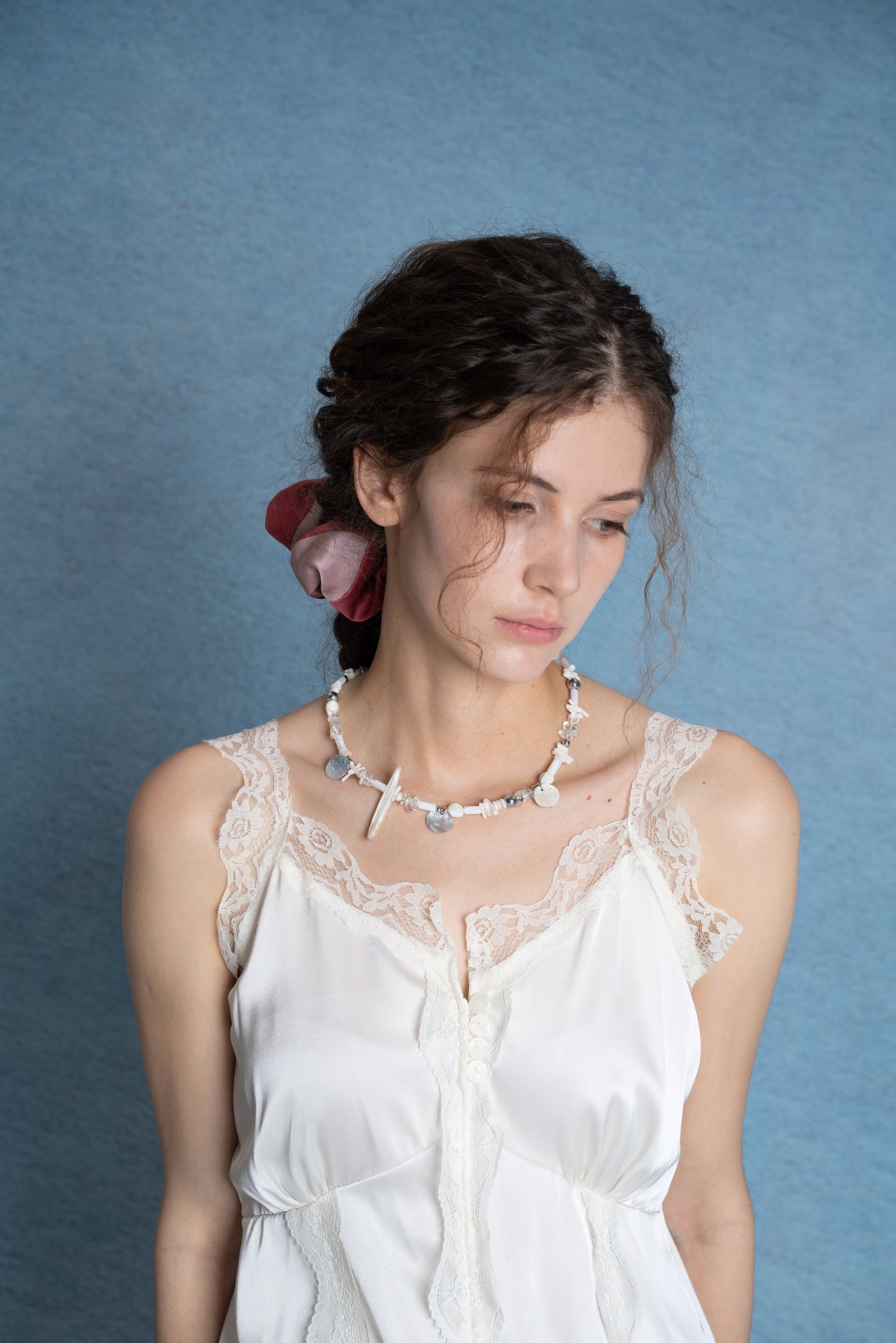 Woman wearing an Ocean Pearl necklace against the blue studio background