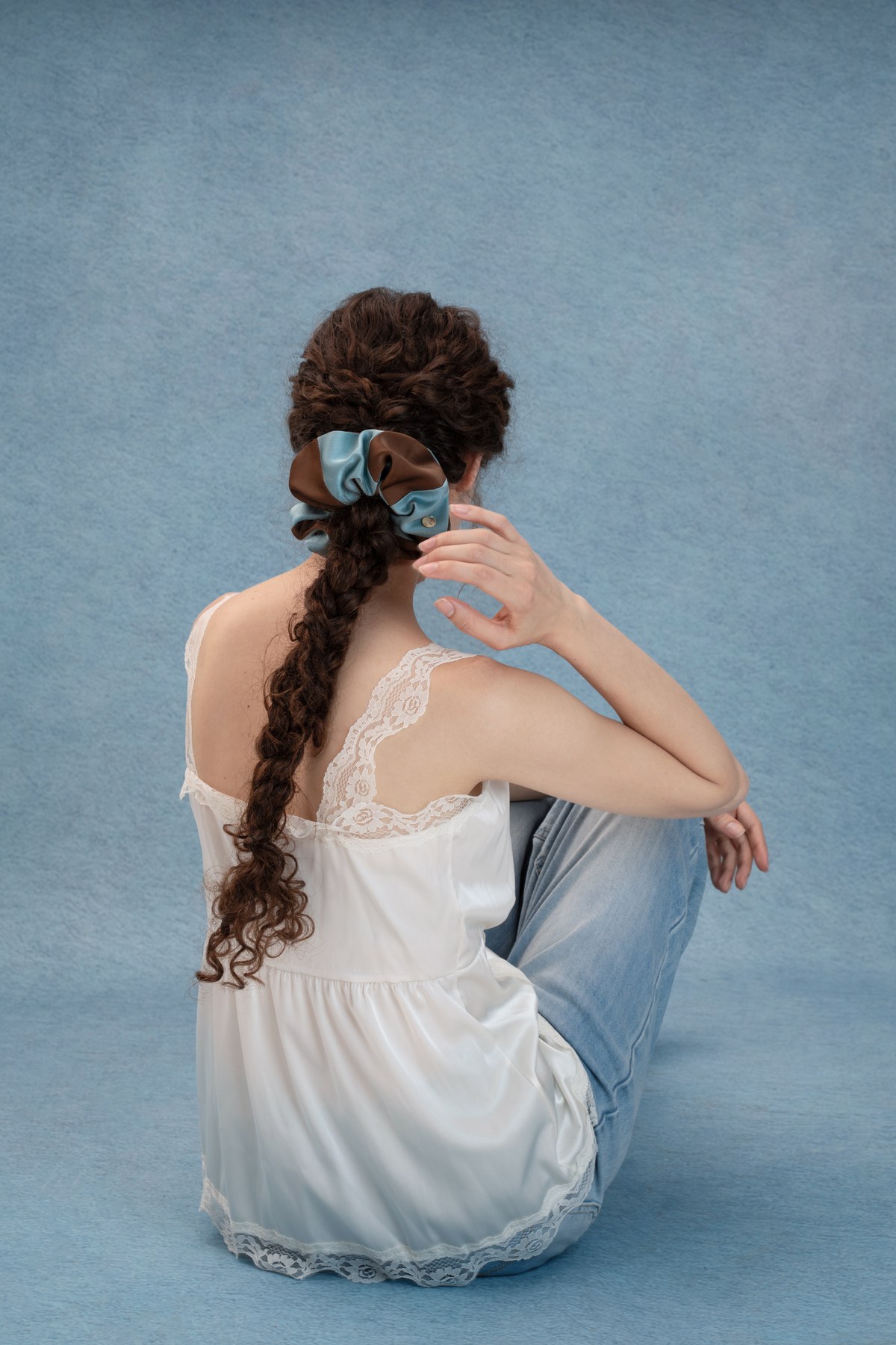 Woman wearing a Mocha Sky scrunchie against the blue studio background